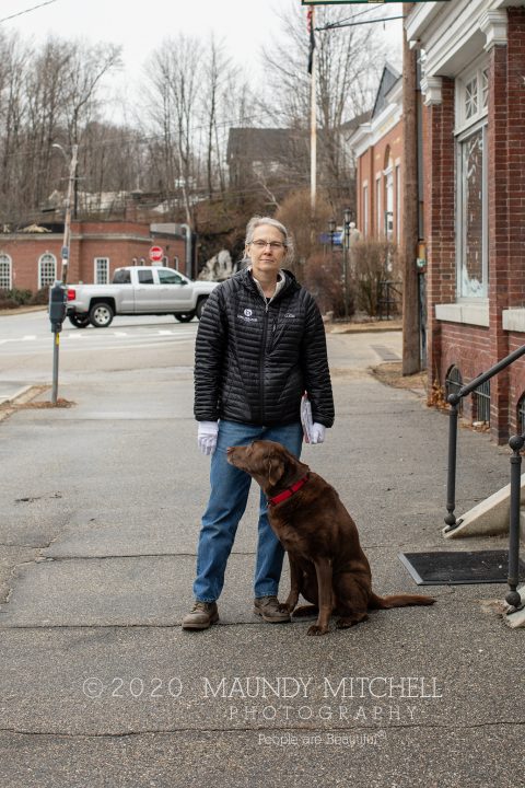 Liz walked past the studio with her dog, Koa, after picking up her mail at the post office. She wears white gloves for protection, and her dog stands on her foot.