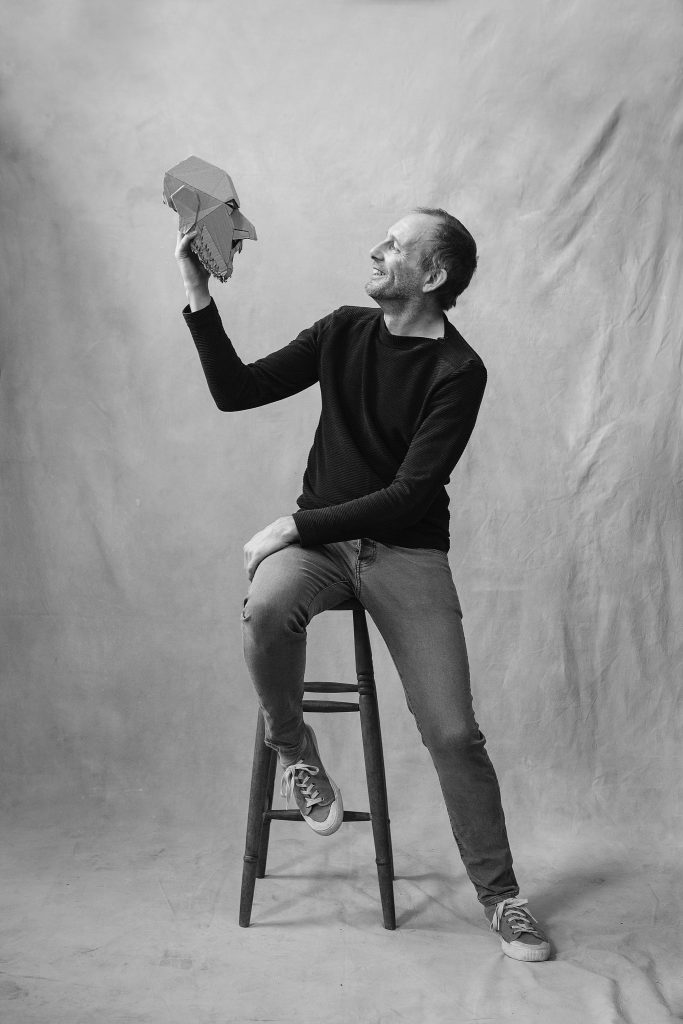 London-based puppeteer Mark Down, laughing at a mask he is holding