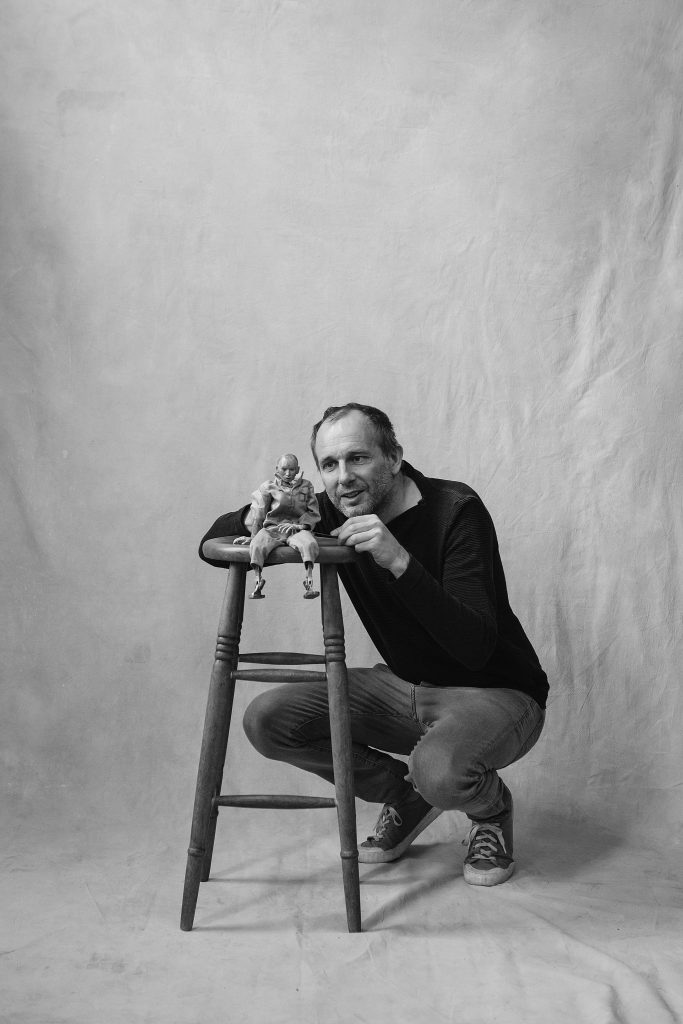 Puppeteer Mark Down, squatting by a stool with a puppet