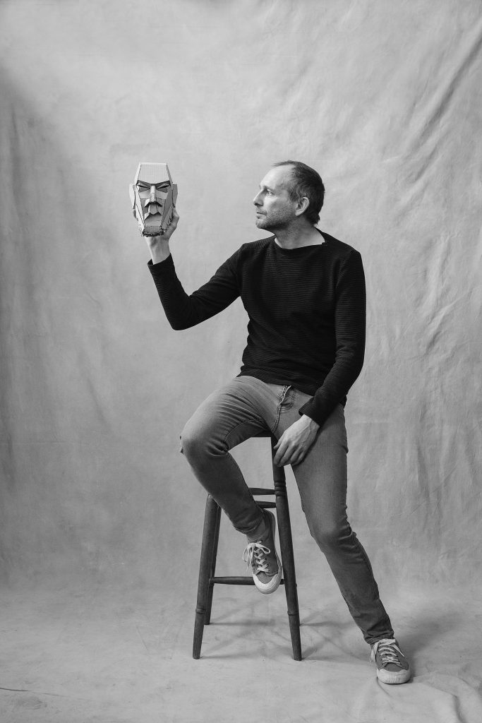 London-based puppeteer Mark Down, seated, holding a mask