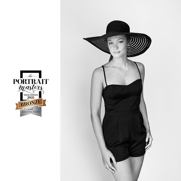 Black and white portrait of teenage girl wearing a wide-brimmed hat and vintage swimsuit