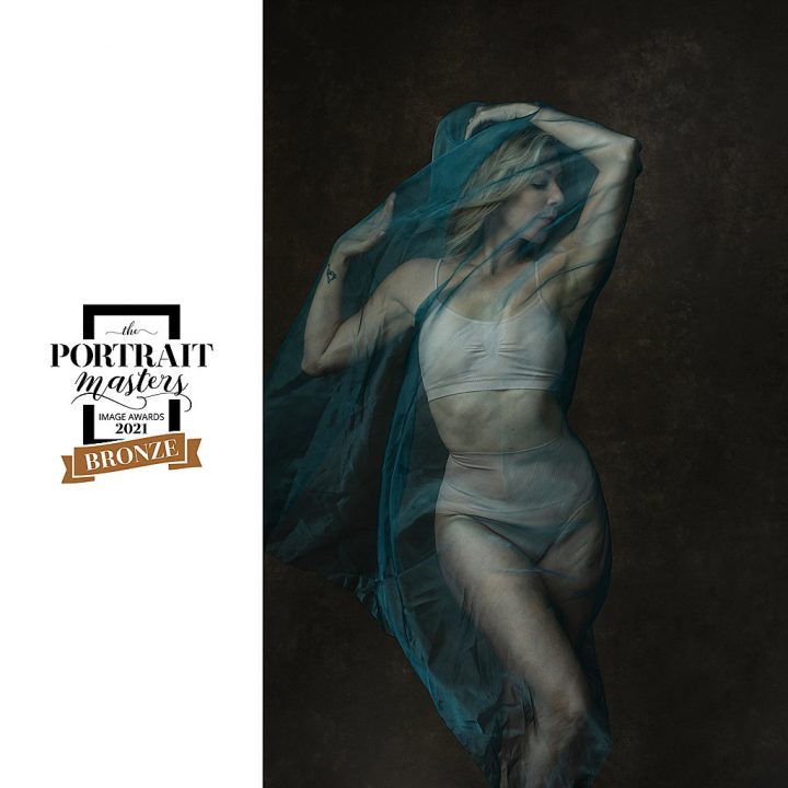Portrait of dancer wrapped in sheer blue fabric