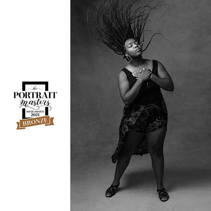 Black and white portrait of woman, flipping her braids in the air