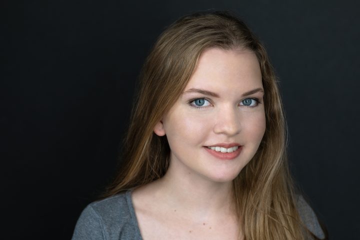 Headshot for a young actor, Chloe, wearing a gray tee-shirt on a black background