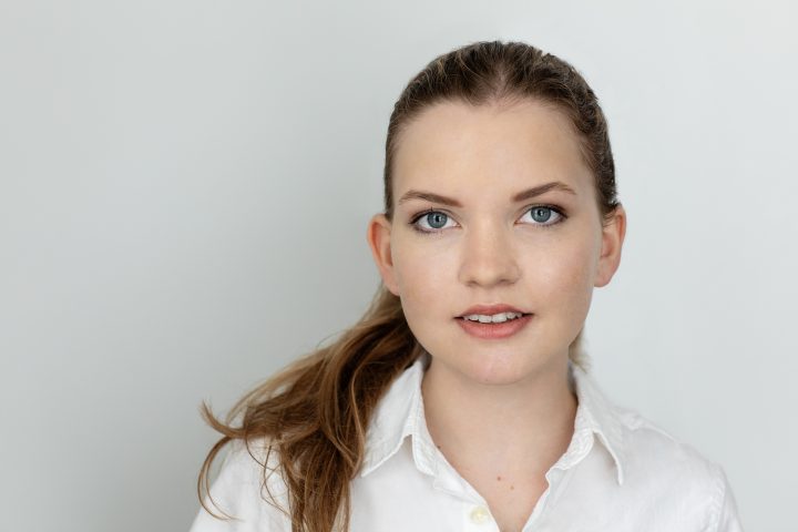 Headshot of teenage girl smiling with light gray background