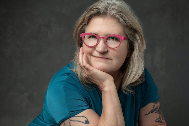 Portrait of Evelyn in teal and pink-framed glasses