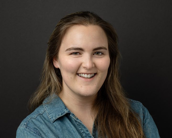 Acting headshot for Anna, who is smiling, on a black background