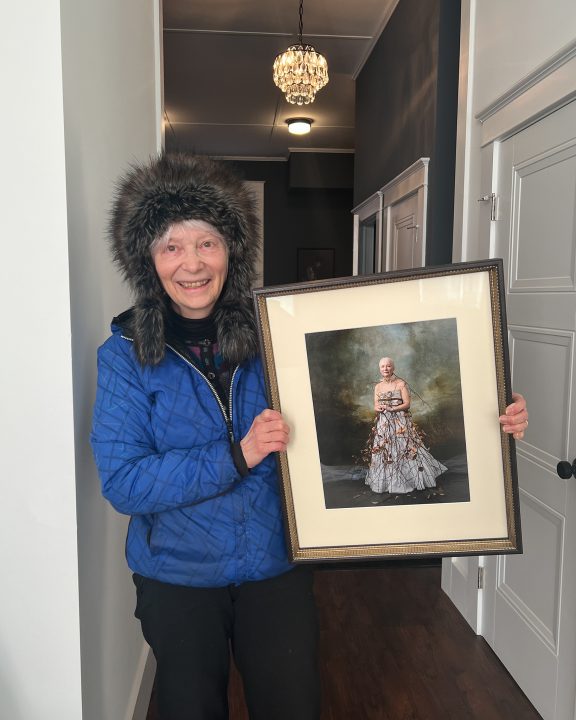 A woman with a custom-framed wall portrait of herself
