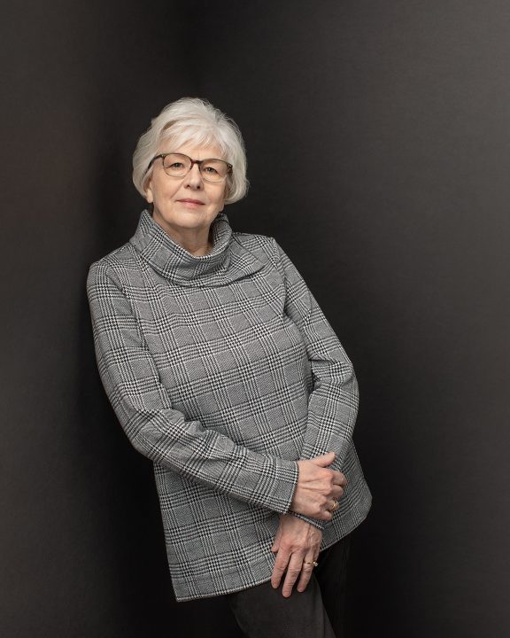 Portrait of quilter Susan Hofstetter in front of black background