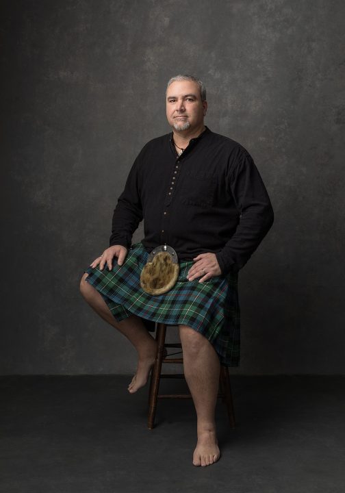 Portrait of a man, seated, wearing a kilt