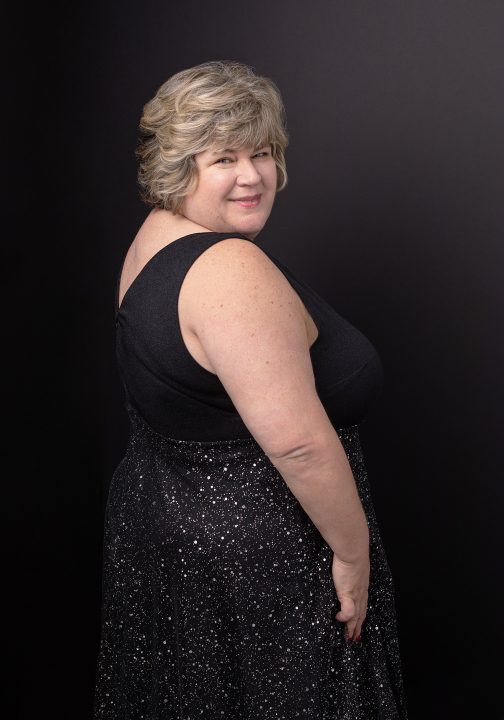 Portrait of Taunya wearing a black dress and looking over her shoulder for the Over 50 Revolution