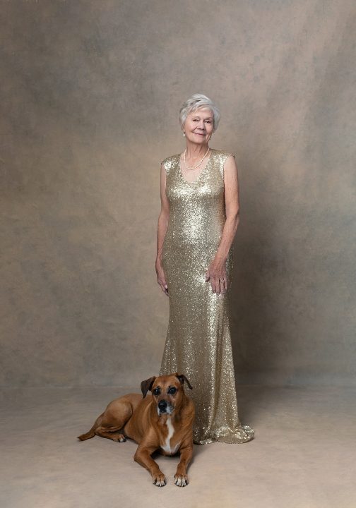 Portrait of Sharon wearing a gold gown, standing with her dog for her photo session for Extraordinary: the Over 50 Revolution