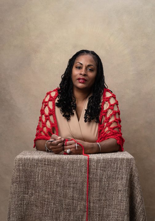 A portrait of Angela crocheting while in prayer, part of the Knitted Together series