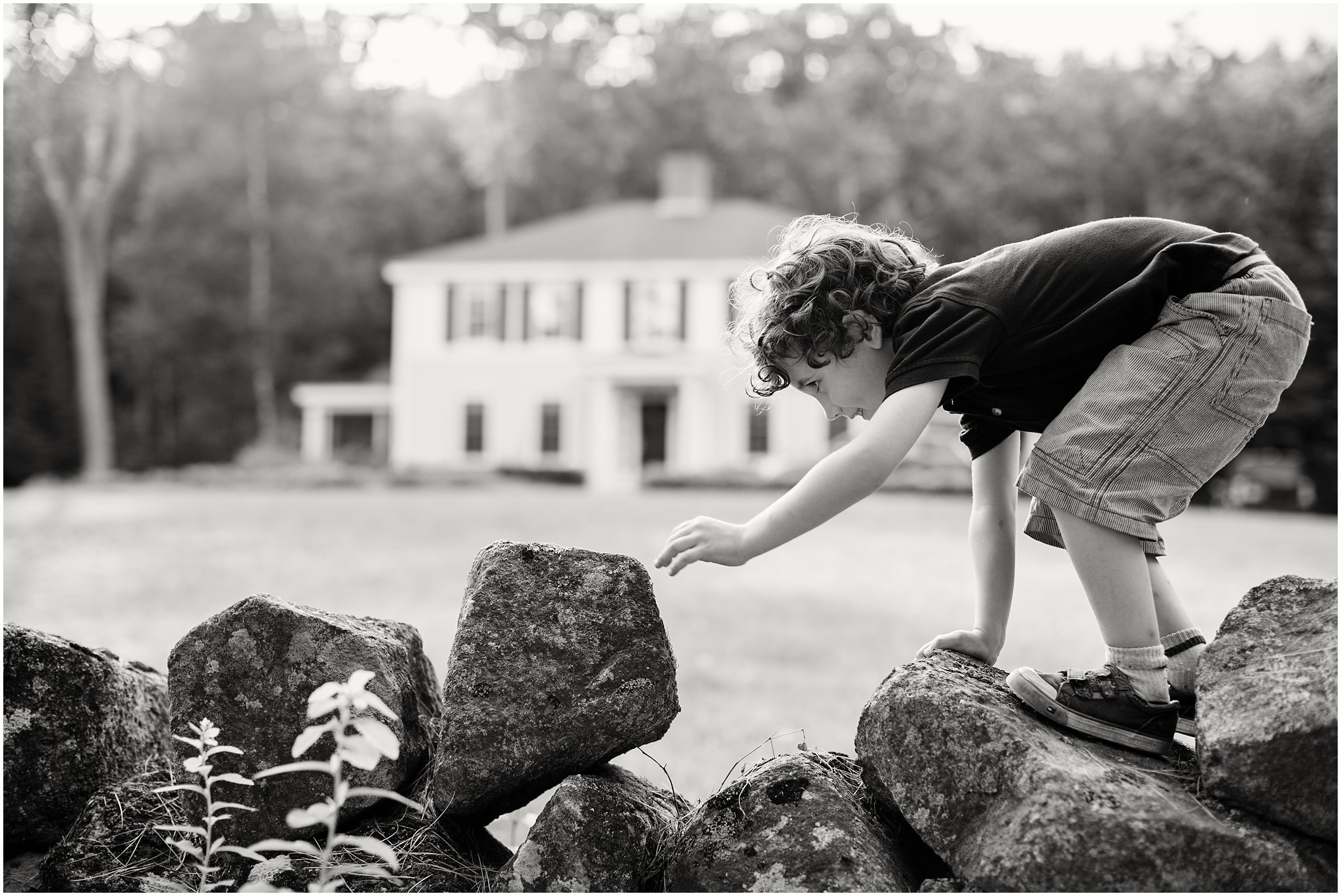 black and white photo of boy climbing stone wall