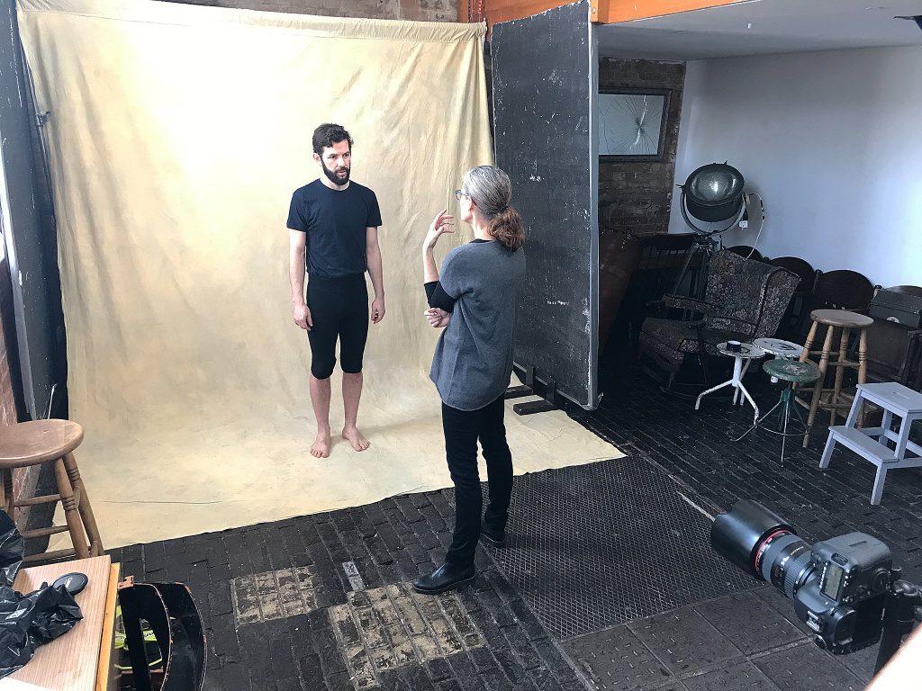 Behind-the-scenes photo of Maundy Mitchell talking with Ramon Ayres, a London mime, before photographing him.