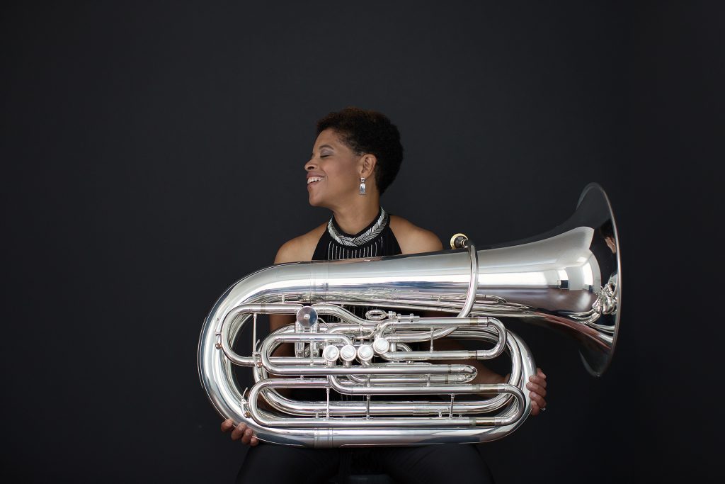 Profile of tuba player Velvet Brown holding a tuba and laughing