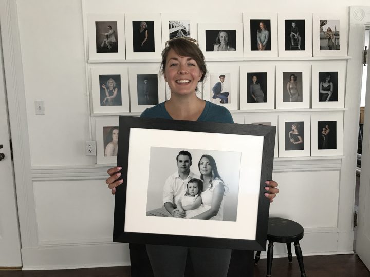 Picture of Kate holding a framed portrait of her with her family