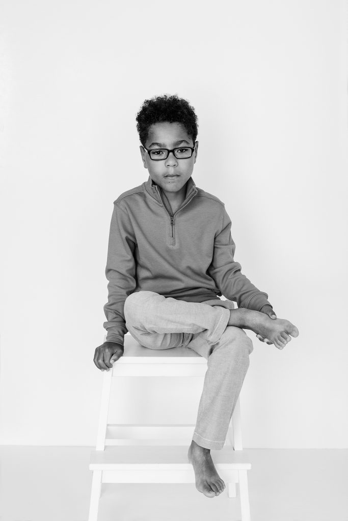 Black and white portrait of Liam, seated with a white background.