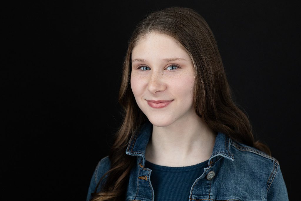 Actor headshot for Sophie Pankhurst.  Teal shirt with jean jacket and black background.