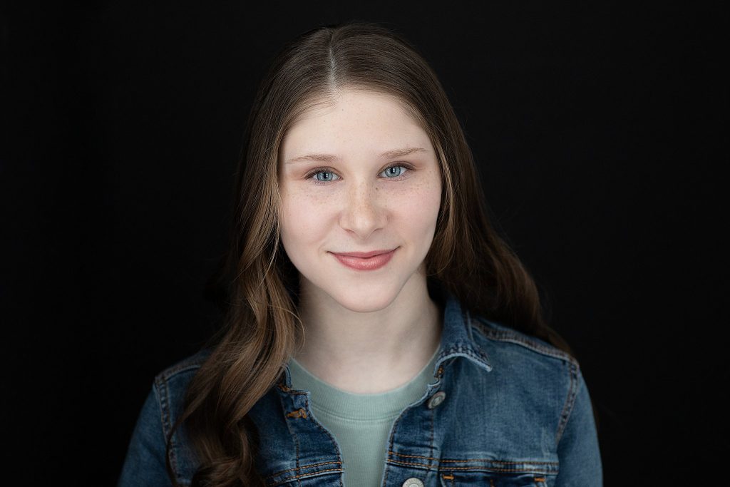 Actor headshot for Sophie Pankhurst in green shirt and jean jacket with black background