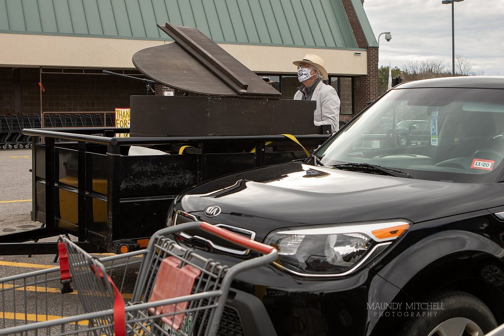 Musician Dave Lockwood sets up his piano and plays in the parking lot of the local grocery store.