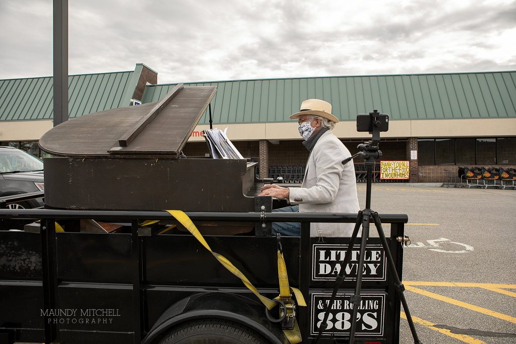 Musician Dave Lockwood sets up his piano and plays in the parking lot of the local grocery store.