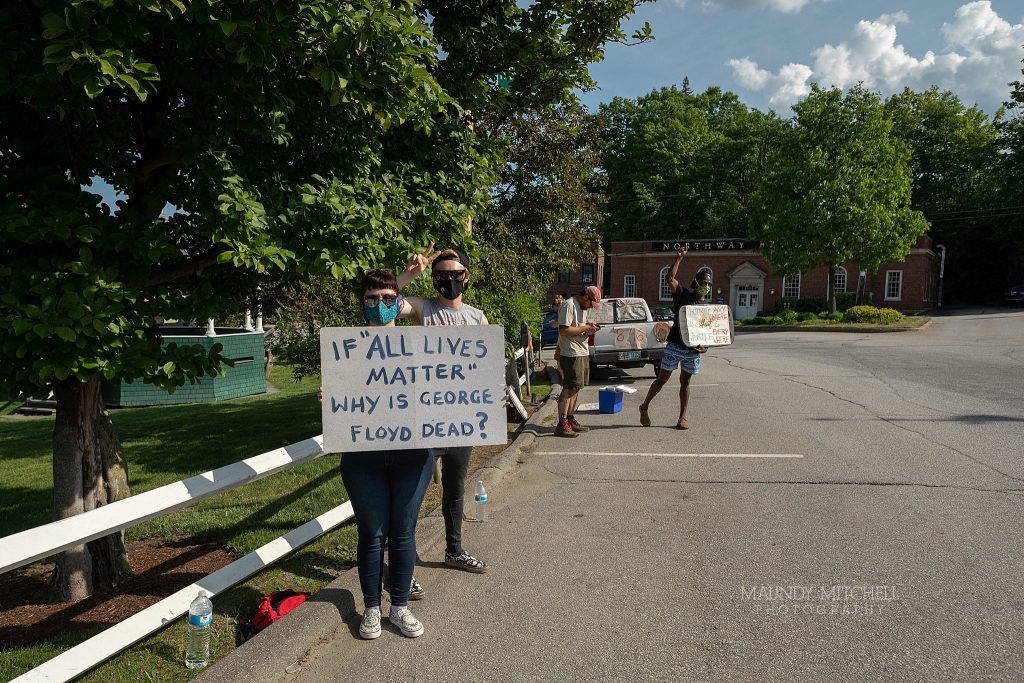 Protesters on the Plymouth, NH town common hold signs.