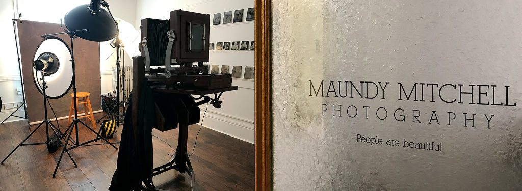 The antique Deardorff 8x10 camera and the tintype studio room's door sticker: Maundy Mitchell Photography - People are beautiful. 