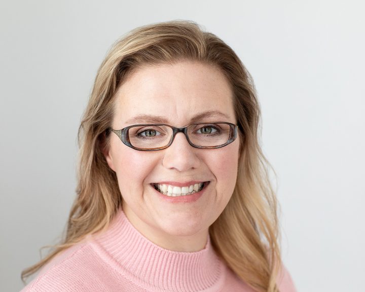 Modern headshot of smiling woman wearing glasses on light background