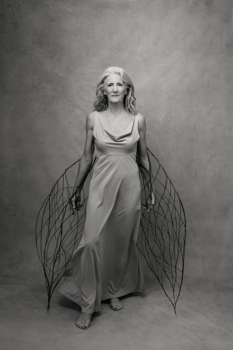 “Phoenix” is a black-and-white portrait of Melinda at age 63, holding a pair of “wings” that she made of sticks from her own land.