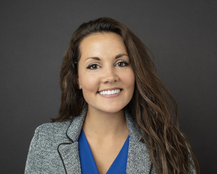 A business professional headshot of a woman with long hair, smiling