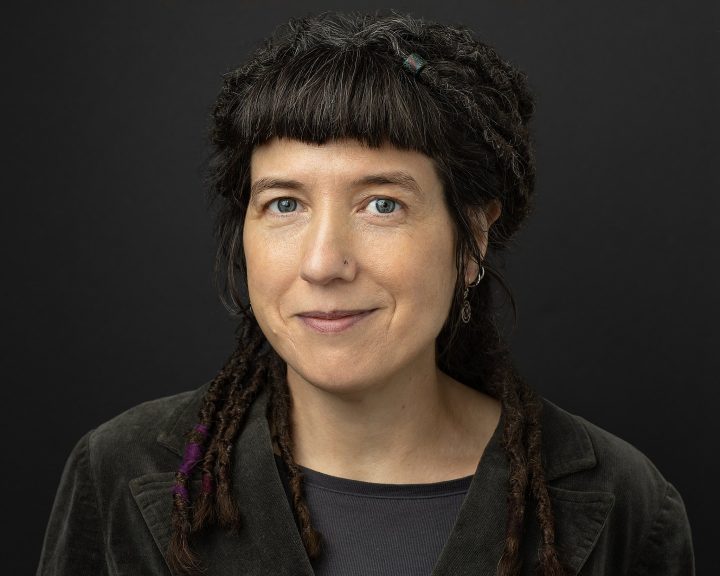 Headshot of Dr. Niki Tulk with dreadlocks and a black background