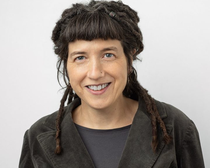 Headshot of Dr. Niki Tulk, performer and writer, smiling in front of a white background