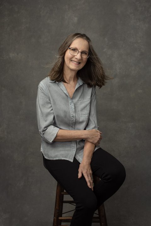 Casual portrait of Nancy, wearing a denim shirt and glasses