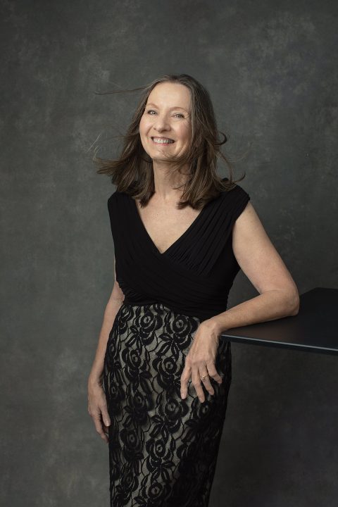 Portrait of Nancy wearing a black lace cocktail dress, with wind in her hair