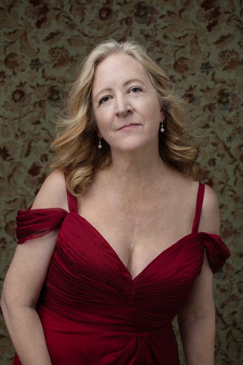 Portrait of a woman in her 60s, wearing a red silk dress