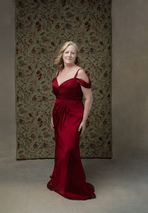 full length portrait of a woman in her 60s wearing a red silk gown