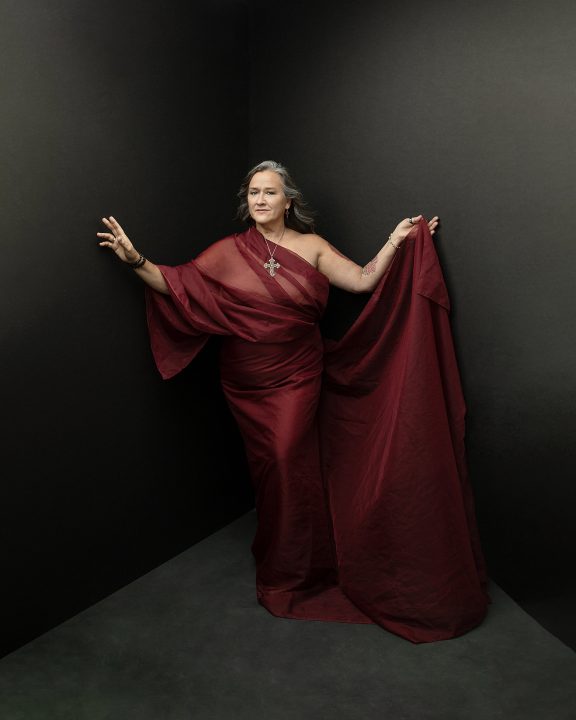 A religious-themed corner portrait of a woman draped in red, standing