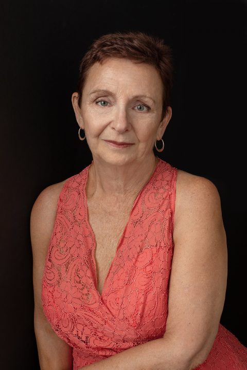 Portrait of a woman with short hair wearing a coral lace dress