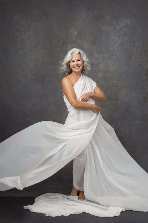 A happy woman dancing in white fabric