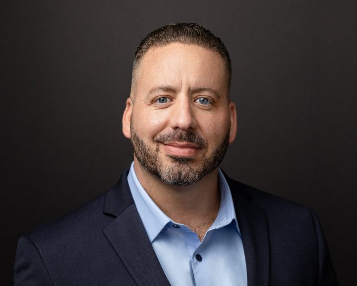 A business headshot with a dark background for a NH Realtor