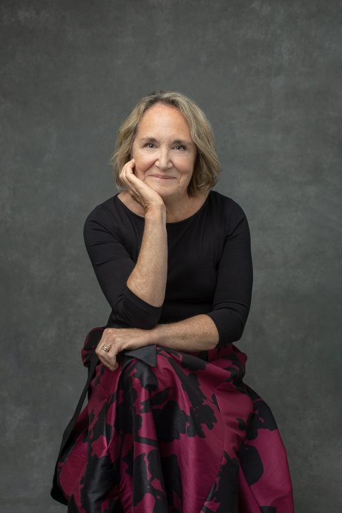 A portrait of a woman in her 60s, wearing a black floral dress