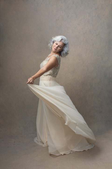 A woman in her 60s, dancing in a cream-colored gown