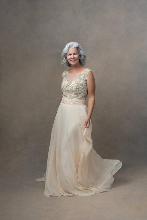 Portrait of a woman in her 60s wearing a cream-colored gown