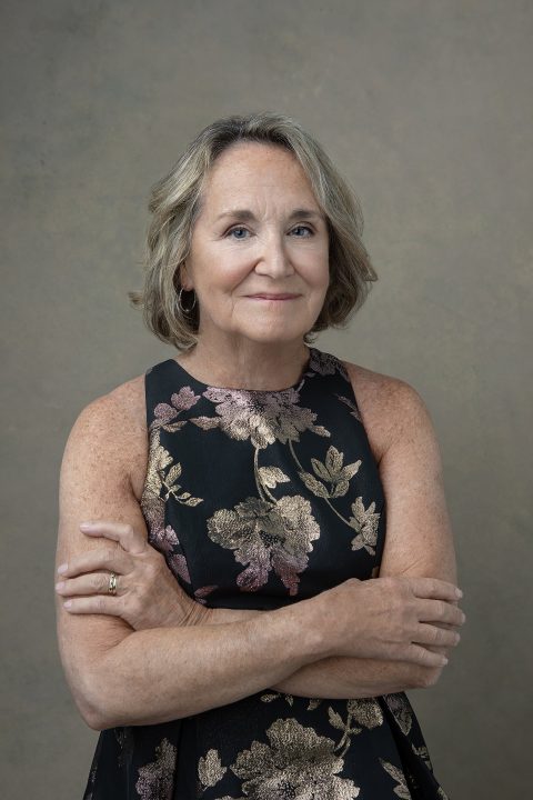 A portrait of a woman in her 60s, wearing a floral dress