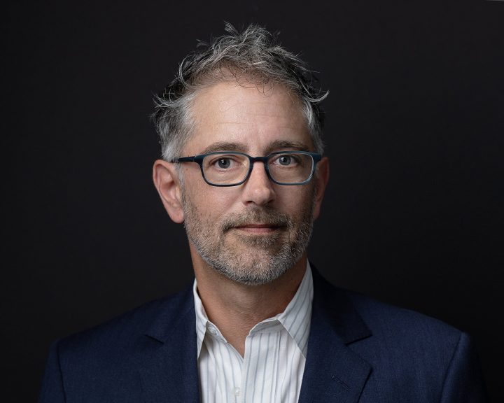 Headshot for John, who is wearing glasses and a suit coat, with a black background.  He wrote, "What a great experience..."