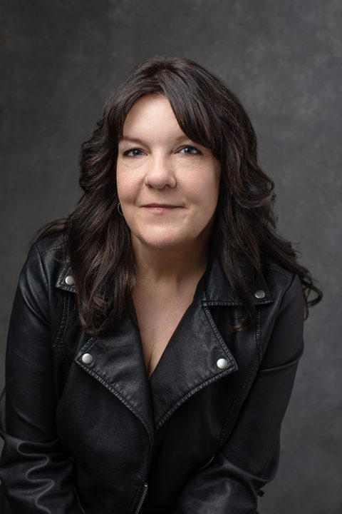 Portrait of Kree leaning forward, wearing a black leather jacket