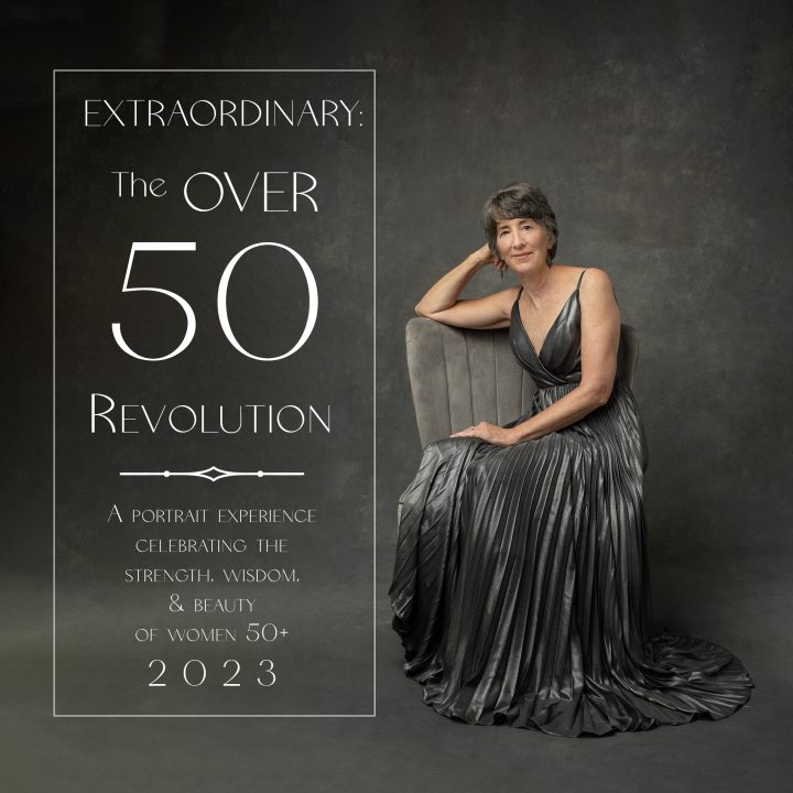 Introducing Extraordinary: the Over 50 Revolution 2023 - a portrait of Andrea in a silver-gray dress sitting in a gray velvet chair in front of a hand-painted gray backdrop