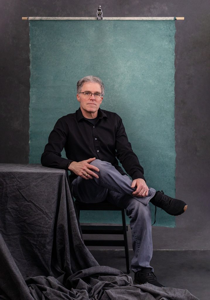 Photo of portrait painter Paul Mock with teal backdrop