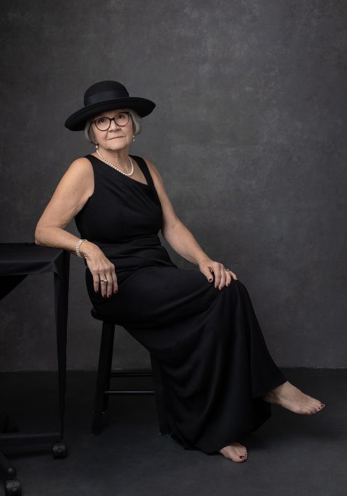 Portrait from Extraordinary: the Over 50 Revolution - Rebecca reclining, wearing a black dress and hat